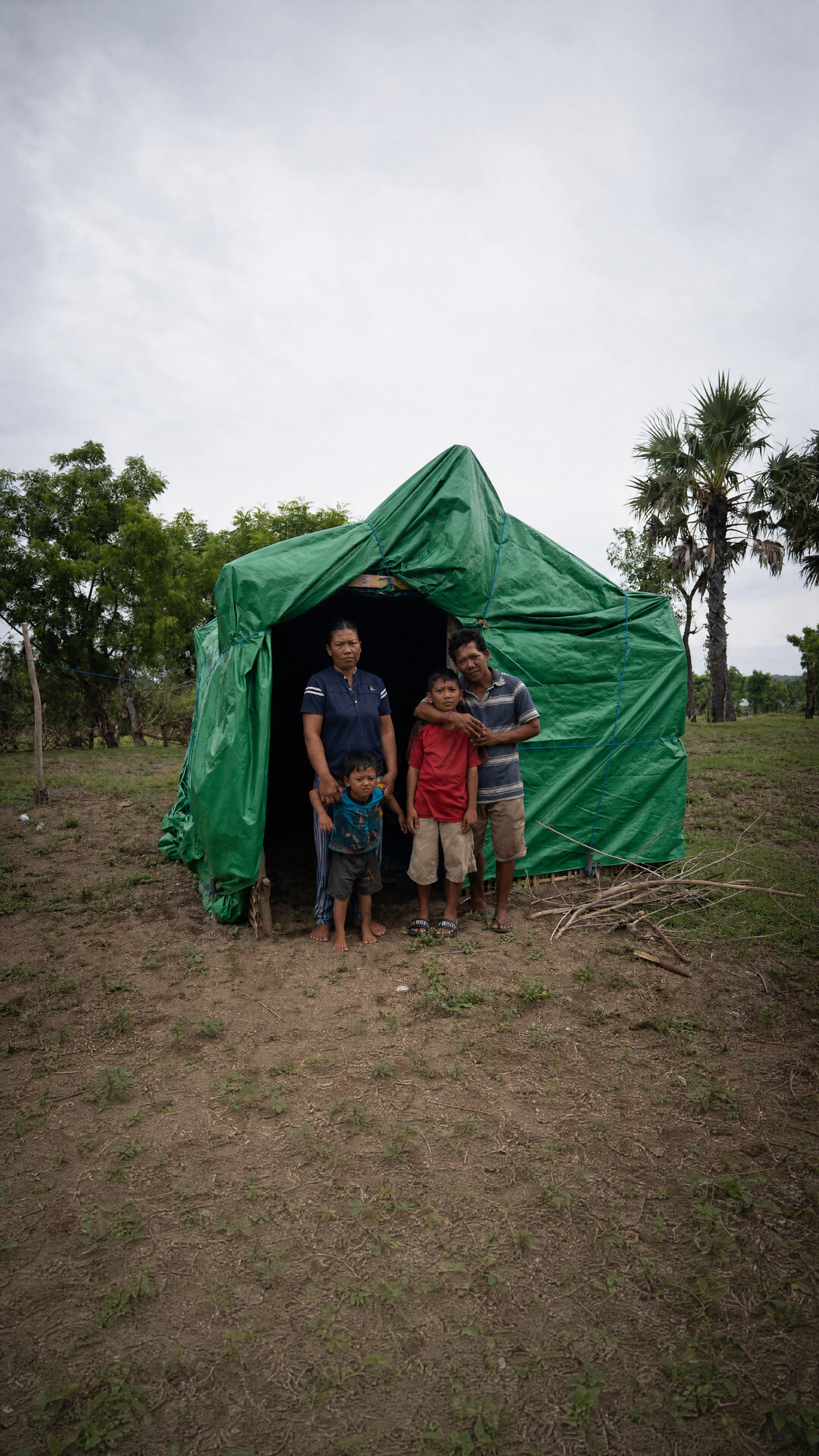 A family outside their tarp shelter, before Rescue 2000 built their home